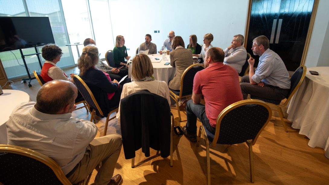 Consortium members discuss on small tables. Photo by Rob Fraser